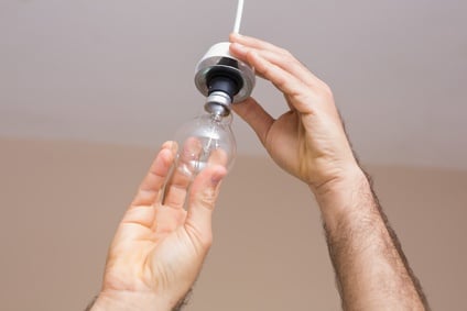 Property maintenance - technician installing new light bulb in rental apartment