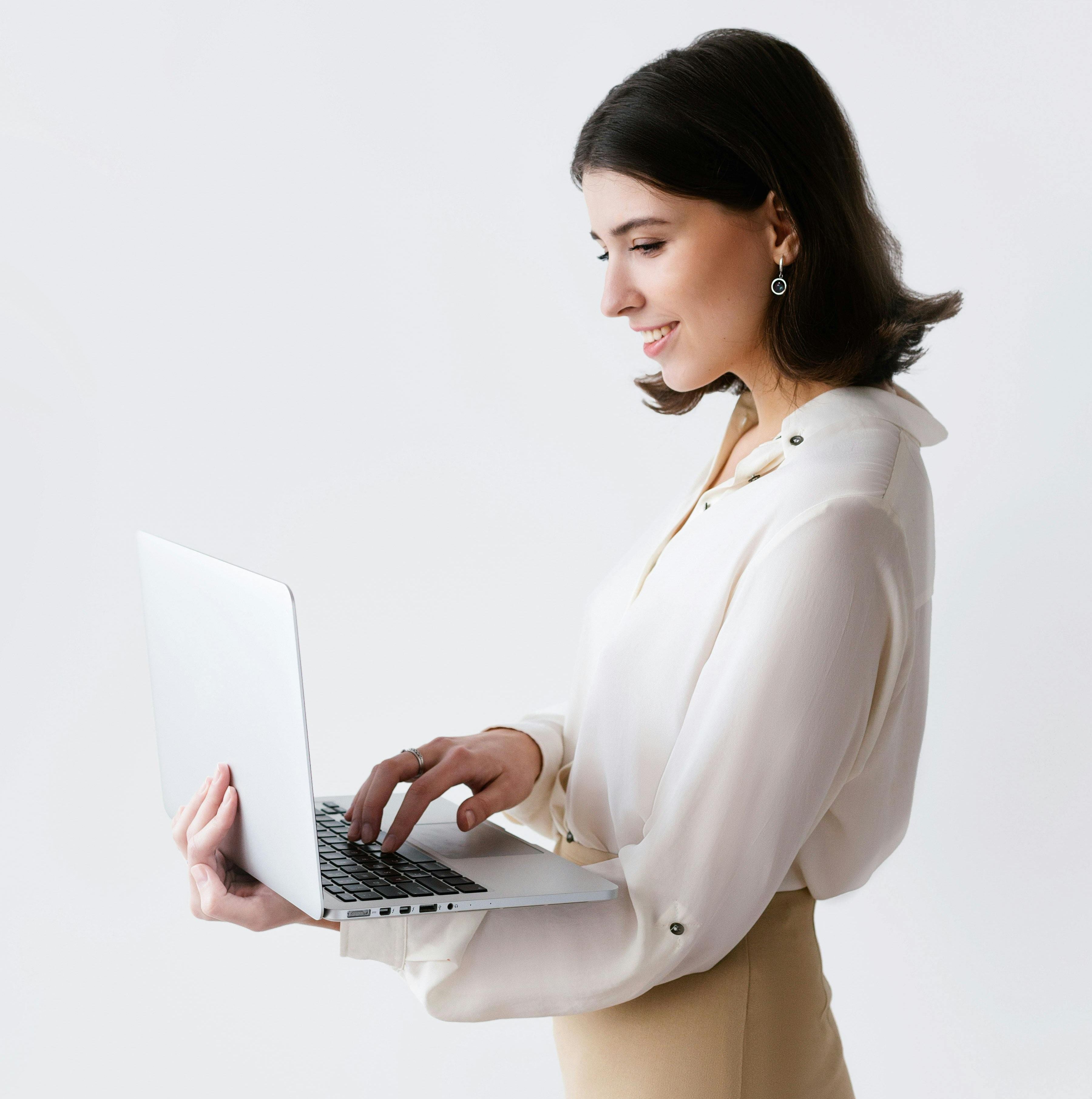 Professional woman using laptop in bright, minimalist space. Modern architecture with clean lines and natural light, ideal for executive rentals.